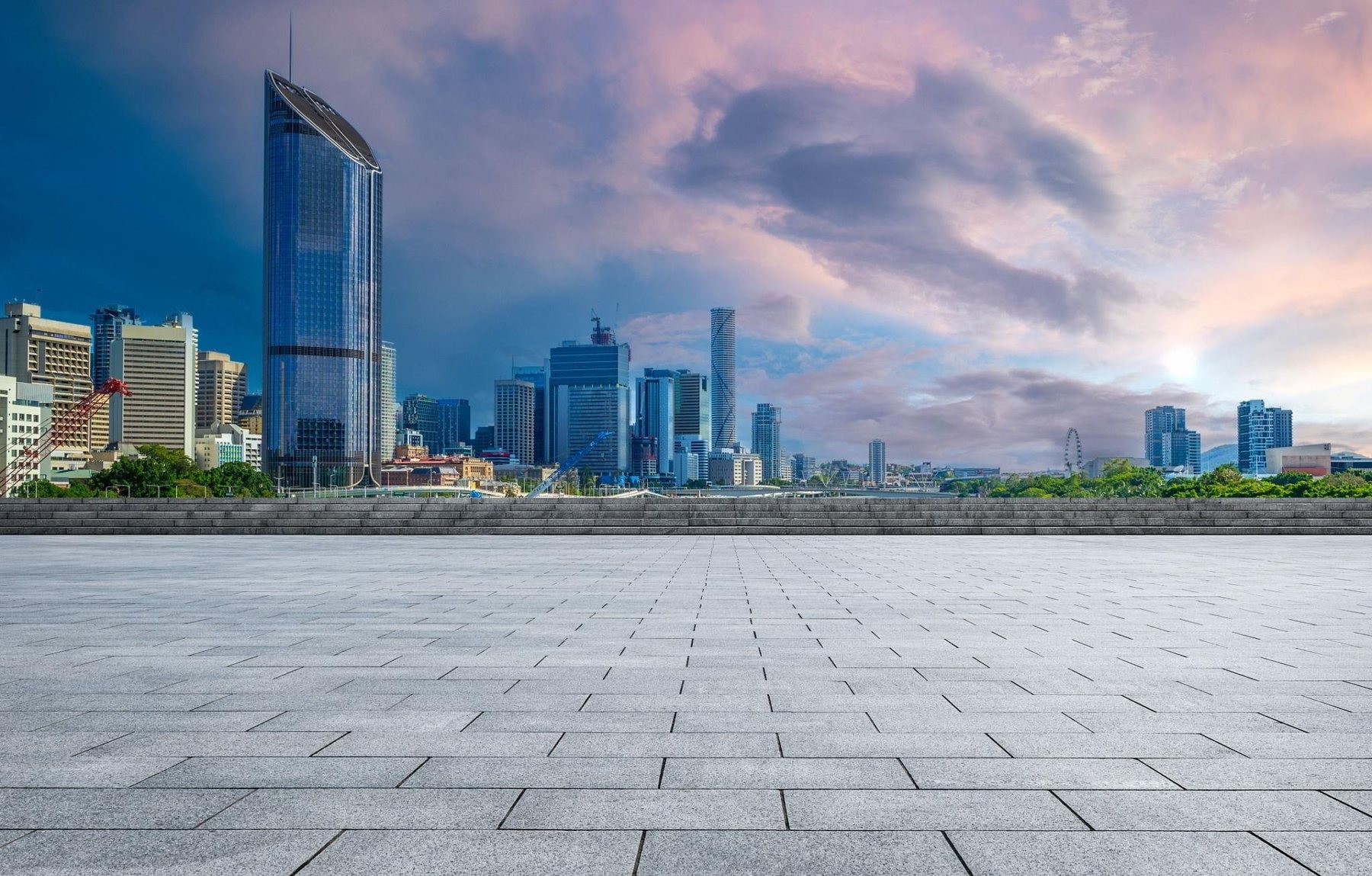 An open city plaza at dusk with a skyline of towers in the distance